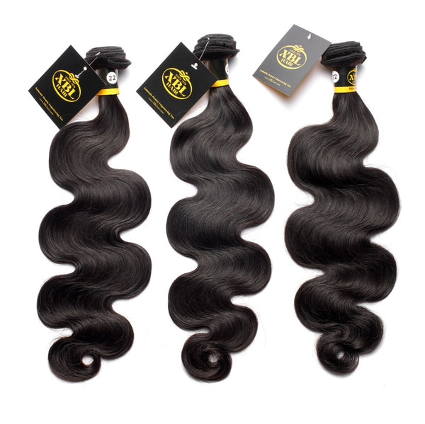 Three bundles of body wave hair extensions with natural black color, displayed with tags attached to each.