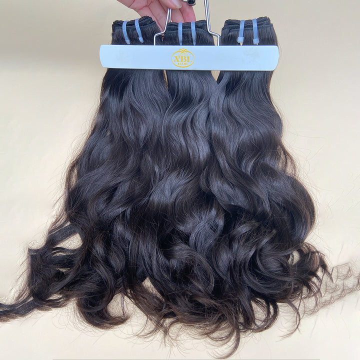 Three bundles of wavy hair extensions in natural black color, displayed on a white background.