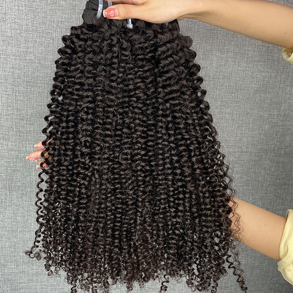 Curly hair extensions held by a person against a gray background