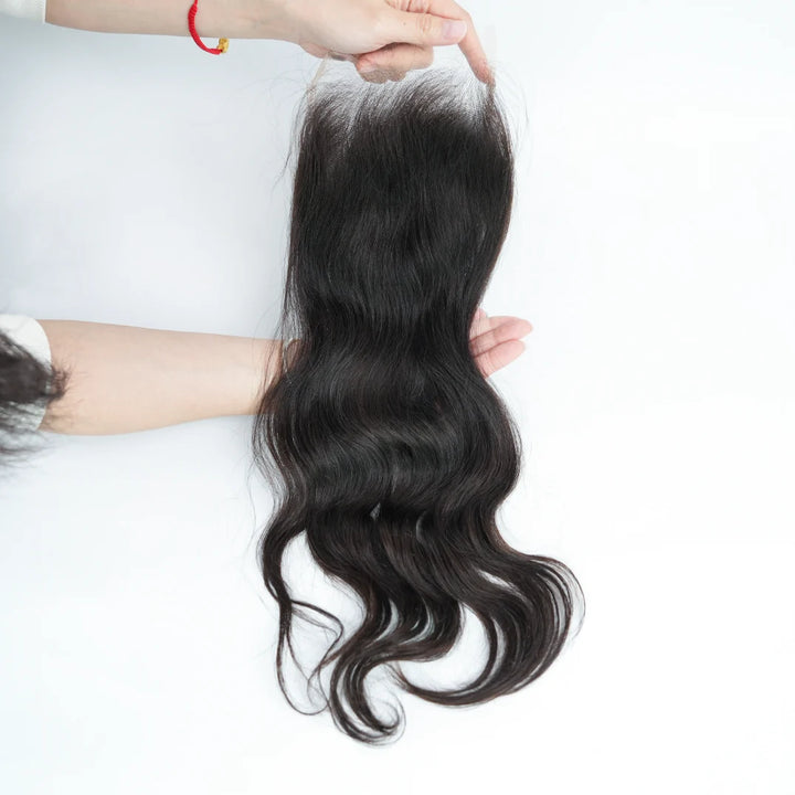 Black hair extensions held by a person on a white background