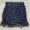 Three pieces of jerry curl human hair extensions laid out on a surface, showing curly black hair.