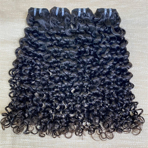 Three pieces of jerry curl human hair extensions laid out on a surface, showing curly black hair.