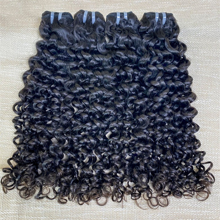 Three pieces of jerry curl human hair extensions laid out on a surface, showing curly black hair.