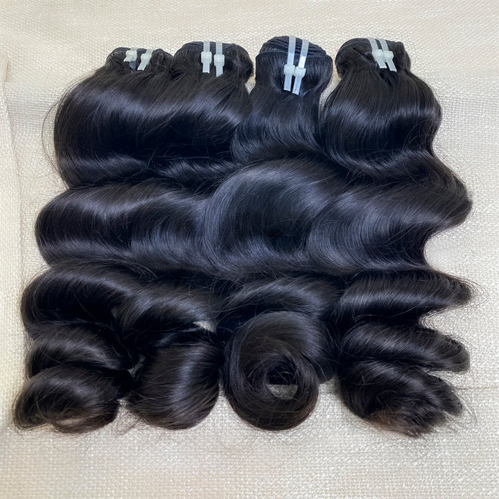 Three bundles of loose wave virgin human hair extensions laid out on a surface.
